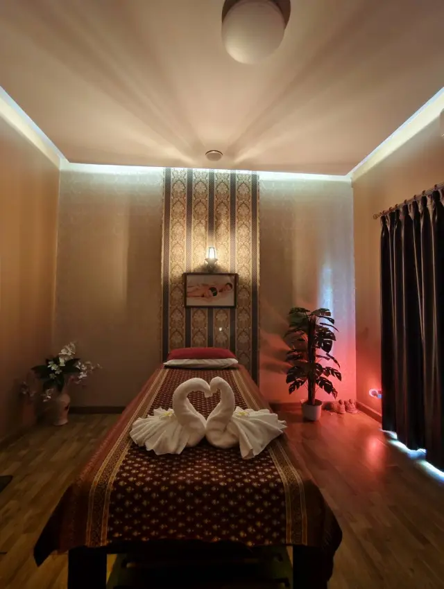 Massage bed topped with swan-shaped towels in a softly lit room at Ai Oon Massage Lanna
