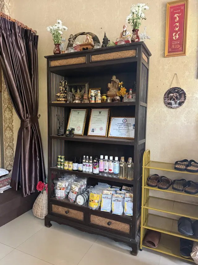 Wooden shelf with figurines, certificates, massage oils and sandals at Ai Oon Massage Lanna