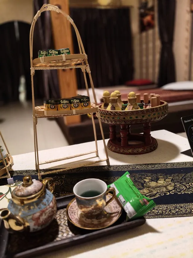 Thai tea set with a tiered rattan stand of snacks on a table at Ai Oon Massage Lanna