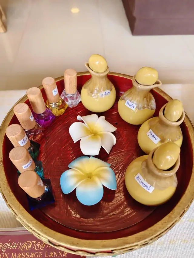 Tray of scented massage oils in clay bottles with plumeria flowers at Ai Oon Massage Lanna