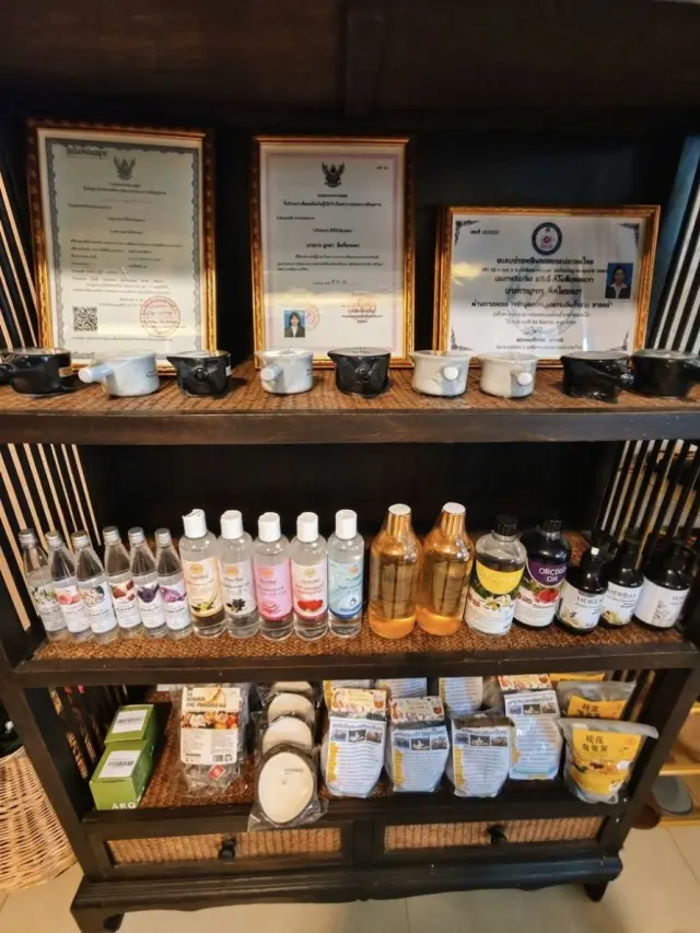 Shelf with framed certificates, teapots and bottled massage oils at Ai Oon Massage Lanna