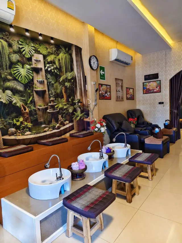 Foot massage station with white basins and recliners beside a jungle mural in Chiang Mai