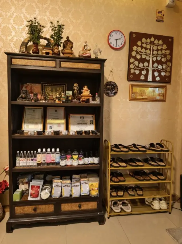 Wooden shelf with certificates, massage oils and a rack of sandals at Ai Oon Massage Lanna