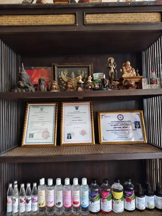 Display shelf of Buddha figures, framed certificates and bottled massage oils at the shop