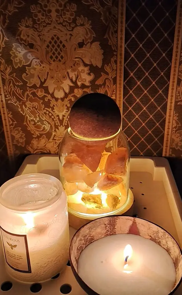 Salt lamp jar and candles on a tray against patterned wallpaper in a Chiang Mai massage room