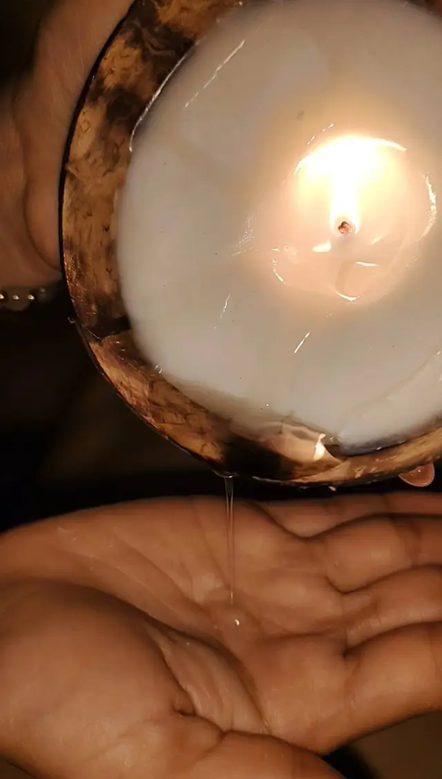 Melted massage candle wax being poured into a hand for a warm candle massage in Chiang Mai